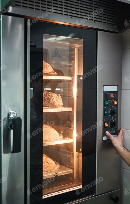 Preview: Baking in oven. Vertical photo of baker's hands touching a button on oven with a lot of freshly