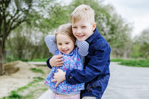 Preview: Little children, brother and sister, hugging, having fun and playing in the park or playground.
