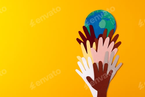 Preview: Paper cut out of multi coloured hands and globe with copy space on yellow background