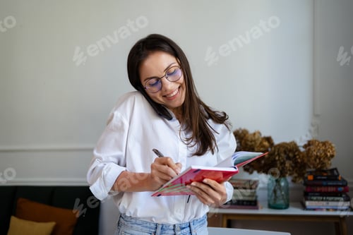Preview: Cheerful Young Beautiful Woman Talking on the Phone and Using Laptop