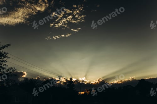 Preview: dramatic amazing sun and sunset light rays through clouds in sky in summer