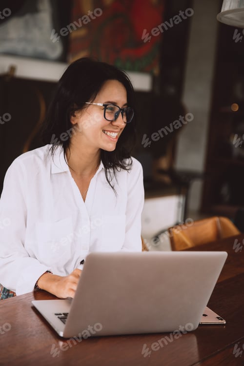 Vorschau: Schöne glückliche Frau mit Brille mit Laptop bei einem Treffen im abgelegenen Coworking-Space