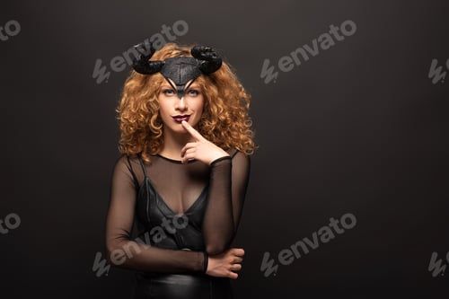 Preview: beautiful pensive woman posing in halloween costume with horns on black
