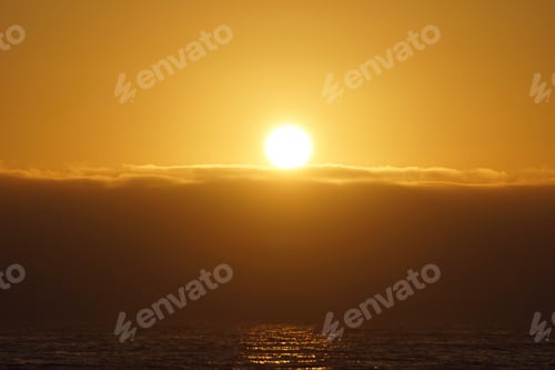 Preview: The bright setting sun over the ocean is getting ready to set behind the coastal fog.