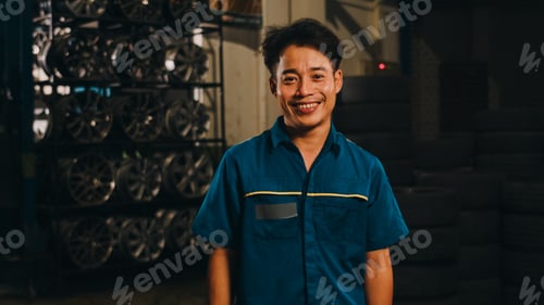 Preview: Professional car mechanic looking at camera and smiling at repair service station.
