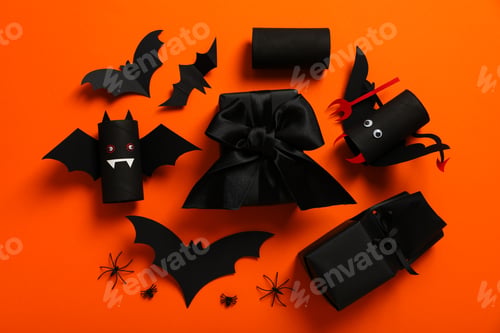 Preview: Gift boxes and paper bats on orange background, top view