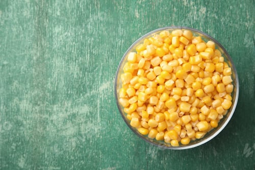 Preview: Bowl with corn kernels on green wooden background, top view. Space for text