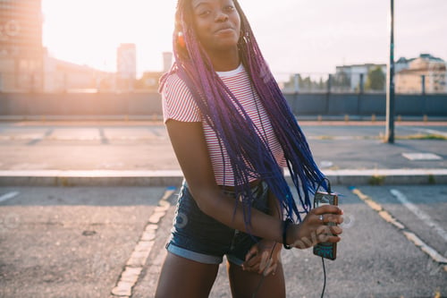 Preview: young black beautiful woman outdoor listening music holding smartphone