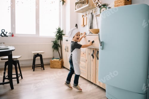 Preview: Young happy mom and her baby cook cookies at home in the kitchen