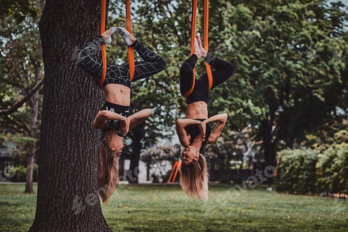 Preview: Two happy cheerful girls are doing exercises upside down
