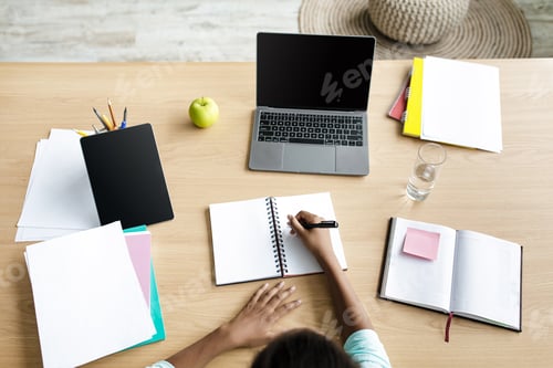 Preview: Adolescent afro american girl student typing on notebook on desk with laptop with blank screen and