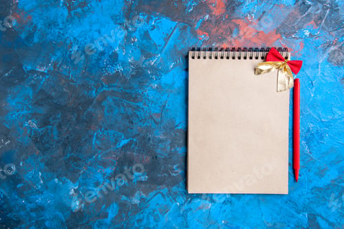 Preview: top view a notepad with little bow red pencil on blue-red background with copy space