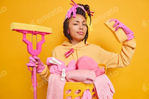 Preview: Self confident dark skinned young woman with braids raises arm shows muscles ready to clean everythi