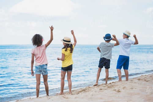 Preview: back view of group of kids throwing stones at seaside together