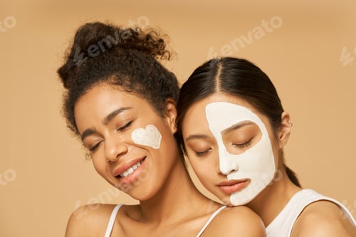 Preview: Close up portrait of two young female friends with facial masks
