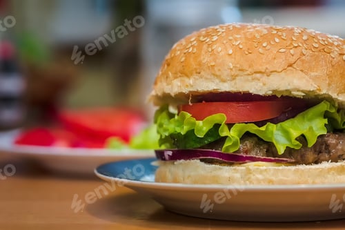 Preview: Homemade burger with tomato and beef patty, fresh toppings on whole grain artisan bun on kitchen