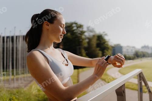 Preview: Young sporty woman checking her performance on smartwach after workout session.