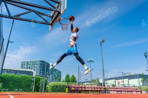 Vista previa: Un jugador de baloncesto alto salta al aro con la pelota en la mano para anotar una volcada espectacular