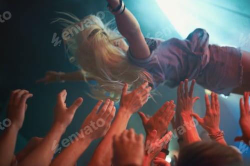 Preview: Surfing on a wave of fans. A young woman crowd-surfing at a concert.