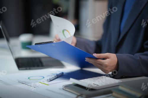 Preview: Business professional reviewing documents with graphs at the office desk