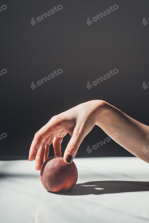 Preview: partial view of woman holding ripe peach in hand on black background