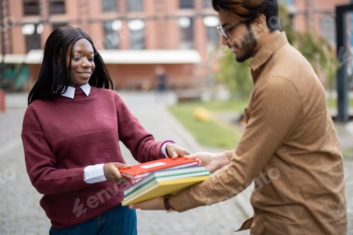 Preview: Indian man giving books to black girl outdoors