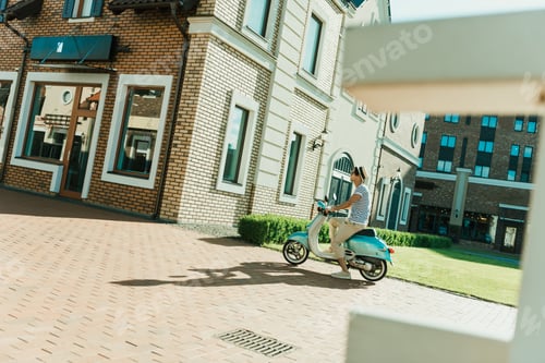Preview: side view of man riding retro scooter on street