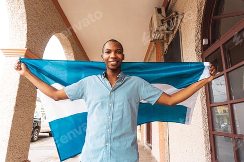 Preview: Portrait of a proud, smiling young African-American man holding the flag of Honduras.