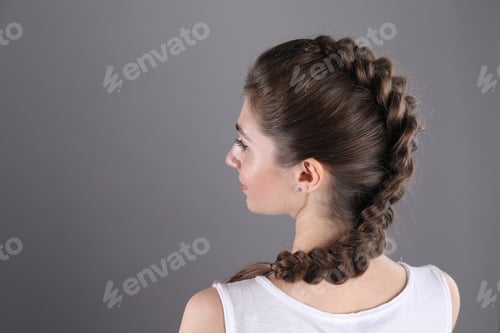 Preview: Woman with braided hair on grey background, back view. Space for text