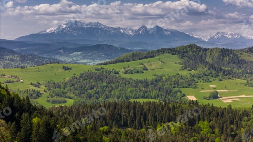 Preview: Aerial drone view over green hills of Pieniny National Park and snowy Tatra Mountains