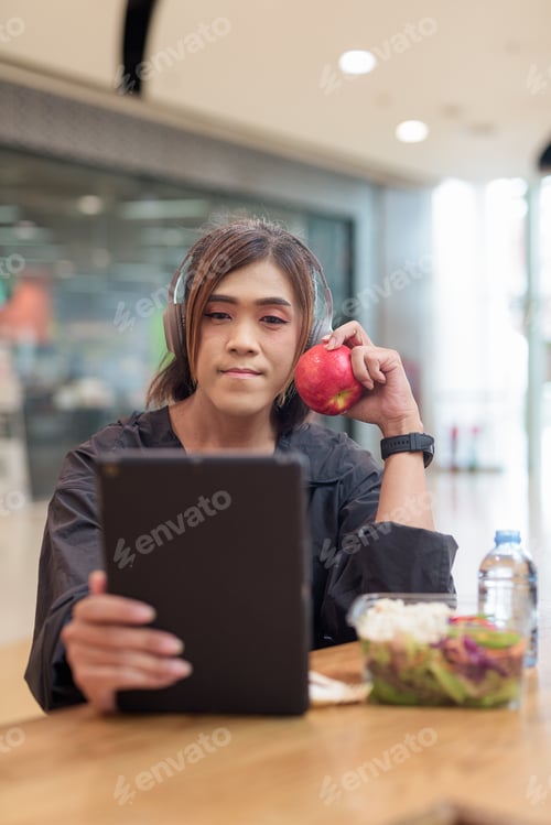 Preview: Transgender non binary woman eating healthy salad in restaurant