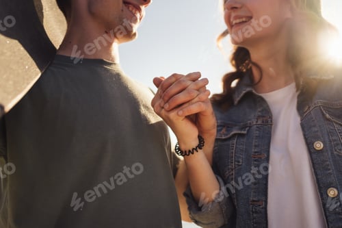 Preview: Happy young people holding hands and smiling, discussing splashed by sunlight
