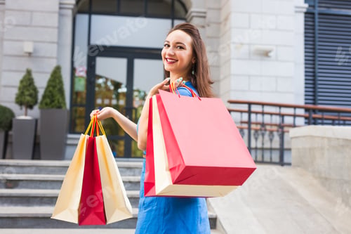 Preview: happiness, consumerism, sale and people concept - smiling young woman with shopping bags