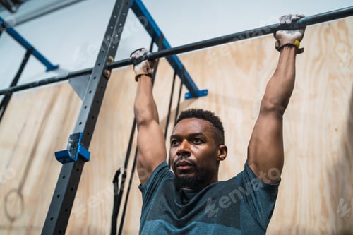 Preview: Athletic man doing pull up exercise at the gym.