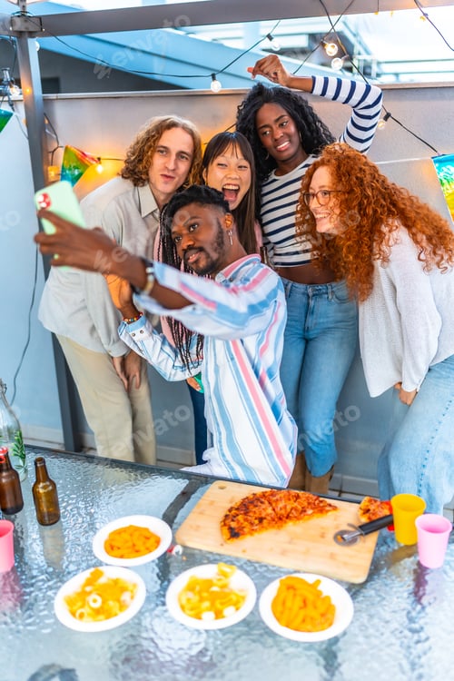 Visualização: Amigos multiétnicos tirando selfie enquanto comemoram uma festa no terraço