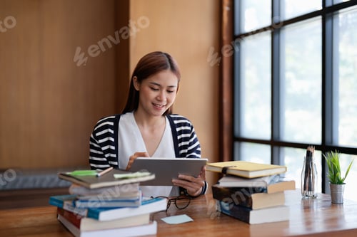 Preview: Young asian woman student working on digital tablet in library.