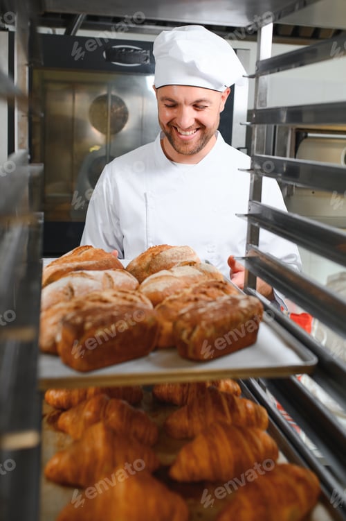 Preview: Male baker holding board with assortment of fresh bread in shop