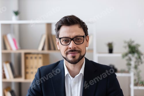 Preview: Professional man with glasses smiling in modern office environment