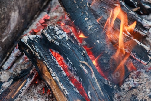 Preview: Red and orange flames emanate from bonfire of burning logs.