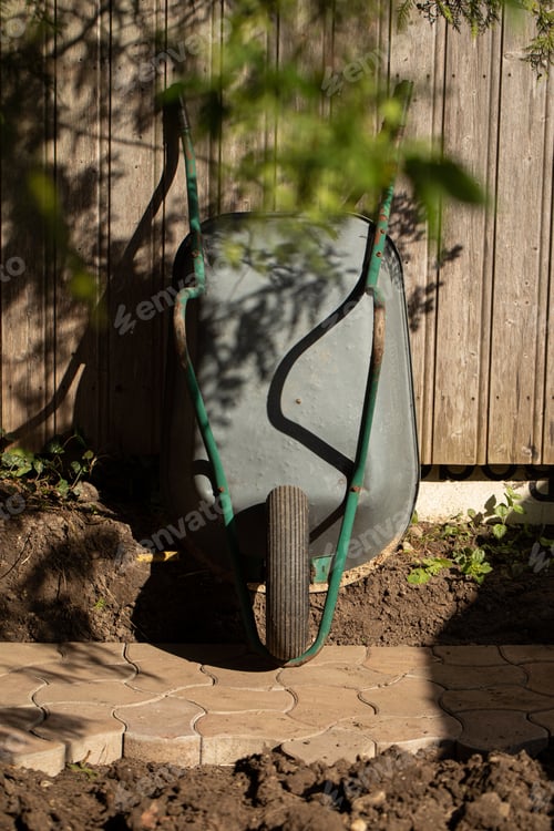 Preview: Wheelbarrow for gardening, standing against a wooden wall. Stone tiles.