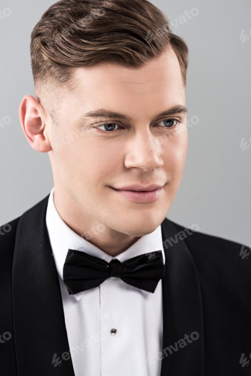 Preview: smiling young man in formal wear with bow tie isolated on grey