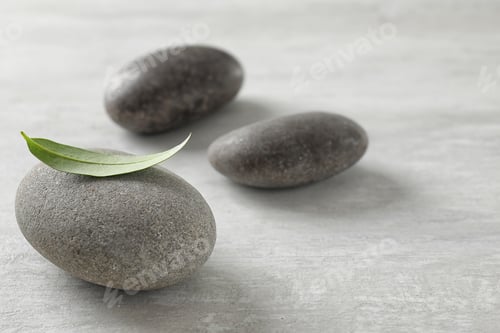 Preview: Spa stones with green leaf on grey background. Space for text
