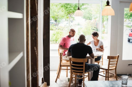 Preview: Two men and a woman sitting at a table in a cafe, having lunch.