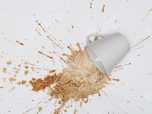 Preview: A tilted mug rests beside a large coffee spill, white background.