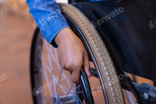 Preview: Gripping wheelchair wheel, african american girl navigating school hallway independently