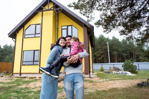 Preview: Happy family in the yard of an unfinished house - purchase of a cottage