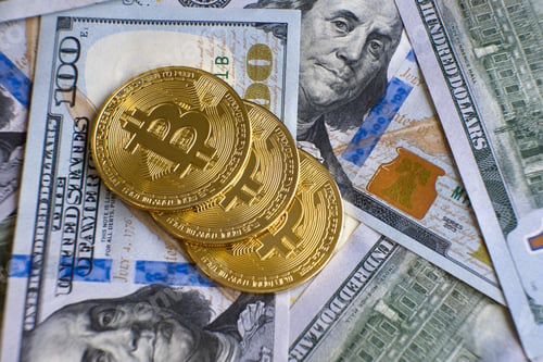 Preview: Close up of metal shiny bitcoin crypto currency coins on US dollar bills.