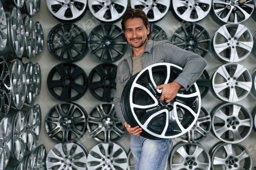 Preview: Silver colored disks, many of them. Man is in the tire fitting car service