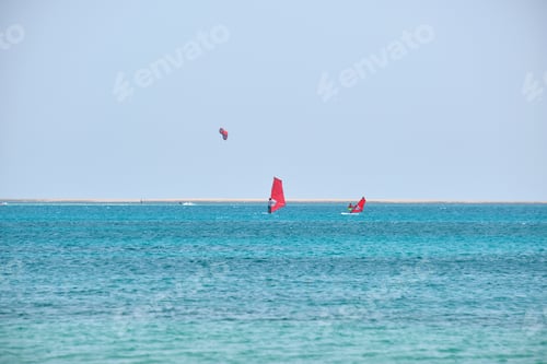 Preview: People sportsmen windsurfing and kite surfing in blue ocean water.