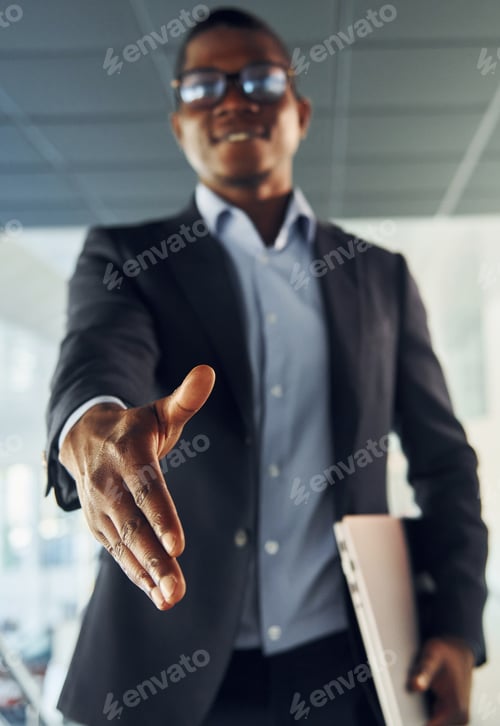 Preview: Handshake gesture. Young african american businessman in black suit is indoors
